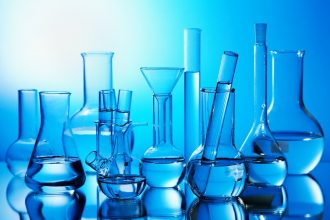clear beakers with clear liquid in them against a blue background. very clinical vibe