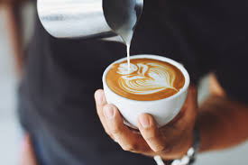 a barista pours milk into a coffee cup