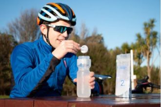 a cyclist pours PowerAmp's Rapid Hydration sachet into his water bottle
