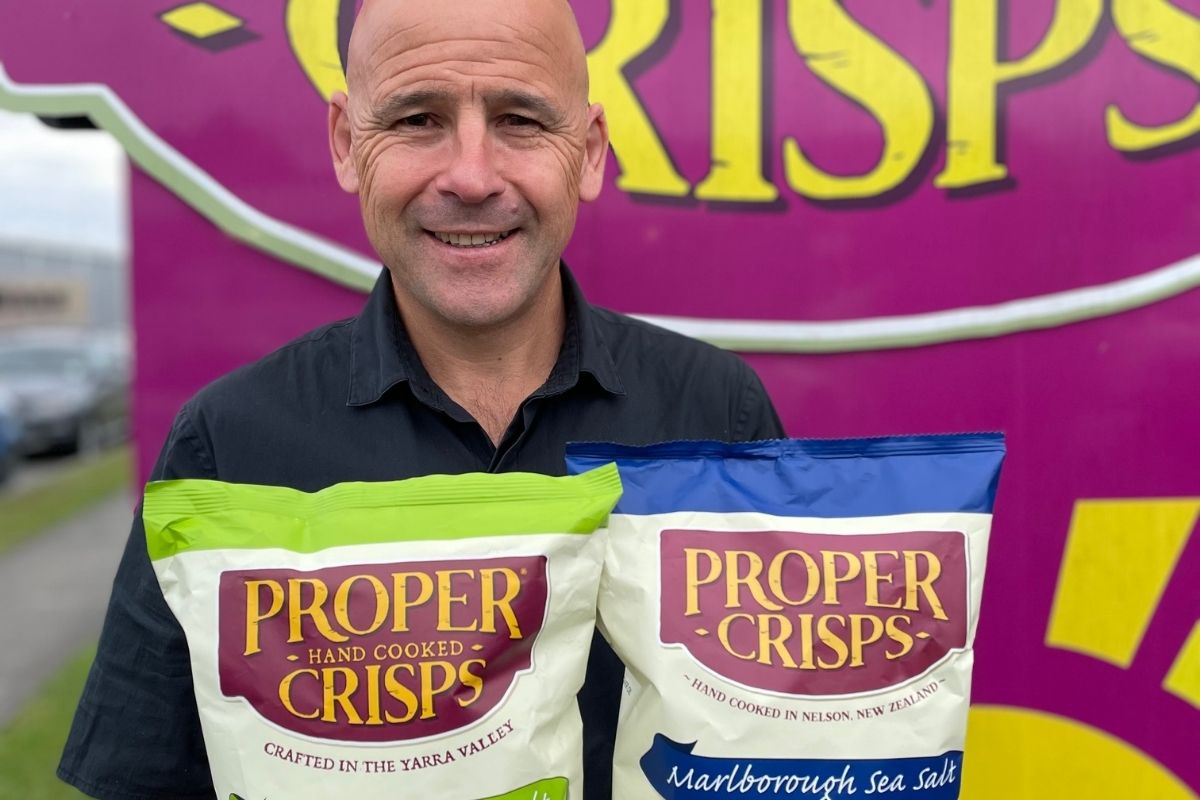 Andy from Proper Crisps, hollding a packet two packets of crisps